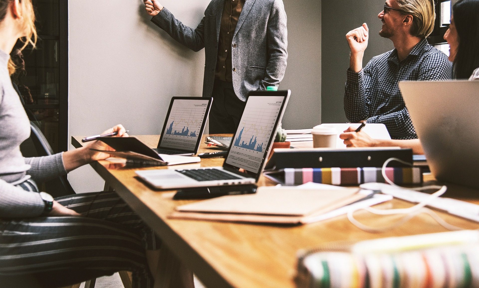 Equipo de trabajo colaborando alrededor de una mesa con laptops y datos
